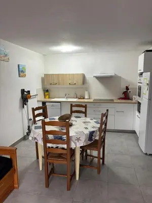 a kitchen with a table and chairs and a refrigerator at Clos des pins- Climatisation-Parking-Draps By LCG in Gruissan