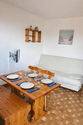 a wooden table with wine glasses and a couch at Charmant appartement proche du port in Gruissan