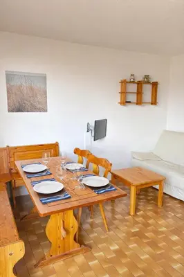 a living room with a wooden table and a couch at Charmant appartement proche du port in Gruissan