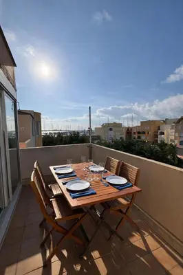 a wooden table with chairs on a balcony with a view at Charmant appartement proche du port in Gruissan