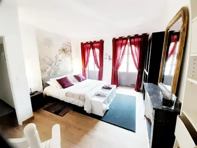 a bedroom with a white bed and red curtains at Aviator in Carcassonne