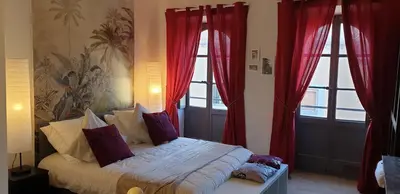 a bedroom with red curtains and a bed with pillows at Aviator in Carcassonne