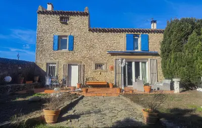 a large stone house with blue shutters on it at Maison Avec Piscine Et Jacuzzi in Rieux-Minervois