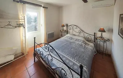 a bedroom with a bed in a room with a window at Maison Avec Piscine Et Jacuzzi in Rieux-Minervois