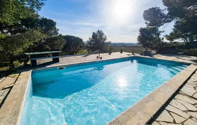 a large swimming pool with blue water at Maison Avec Piscine Et Jacuzzi in Rieux-Minervois