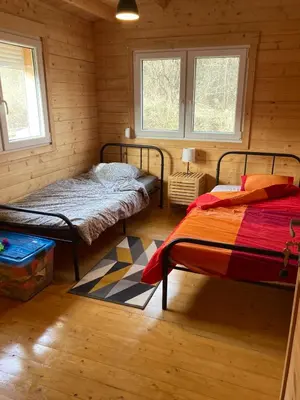 two beds in a room with wooden walls and windows at Au pied du plateau in Campagne-sur-Aude