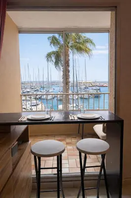 a table with two stools and a view of a harbor at NOUVEAU La Grande Voile Piscine-Parking-Draps By LCG in Gruissan