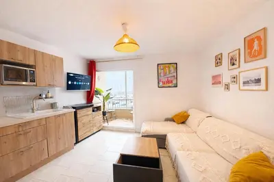 a living room with a couch and a kitchen at NOUVEAU La Grande Voile Piscine-Parking-Draps By LCG in Gruissan
