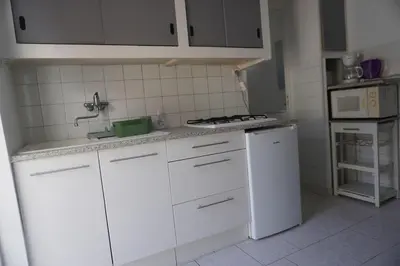 a white kitchen with a sink and a stove at Le Rouget du Port, Sea Terrace and Air Conditioning in Port-la-Nouvelle