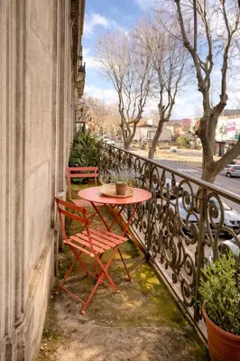 a table and chairs on a balcony with a street at Cozy 48 m2 Narbonne proche gare et centre-ville in Narbonne