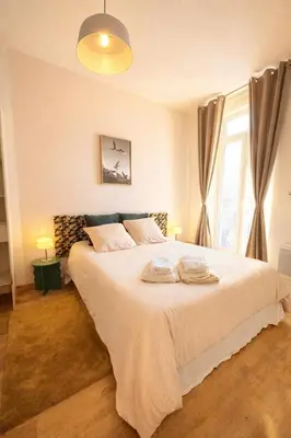 a bedroom with a large white bed with a window at Cozy 48 m2 Narbonne proche gare et centre-ville in Narbonne