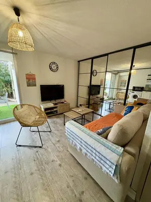 a living room with a bed and a tv at Rez-de-jardin moderne - Accès direct plage in Gruissan