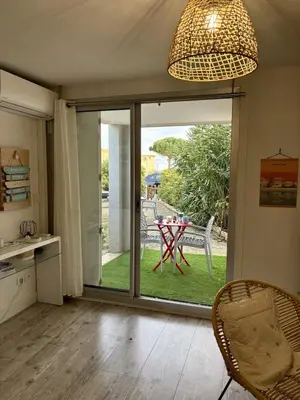 a kitchen with a sliding glass door with a table outside at Rez-de-jardin moderne - Accès direct plage in Gruissan