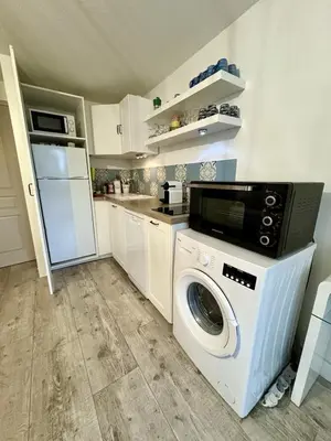 a kitchen with a washing machine and a refrigerator at Rez-de-jardin moderne - Accès direct plage in Gruissan