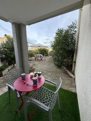 a red table and chairs on a patio at Rez-de-jardin moderne - Accès direct plage in Gruissan
