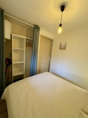 a bedroom with a white bed and a closet at Rez-de-jardin moderne - Accès direct plage in Gruissan
