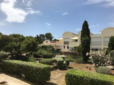 a building with a garden with bushes and trees at Villa de charme avec piscine privée au sel in Gruissan