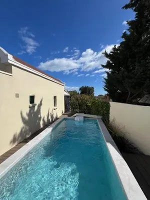 a swimming pool in front of a house with a building at Villa de charme avec piscine privée au sel in Gruissan