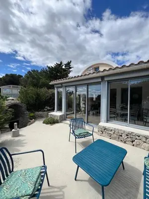 a patio with two blue chairs and a table at Villa de charme avec piscine privée au sel in Gruissan
