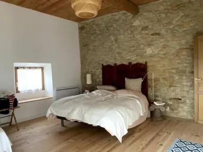 a bedroom with a large bed and a stone wall at Charming house in Tournissan