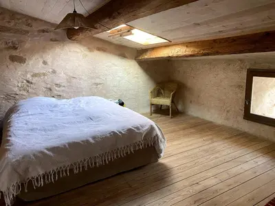 a bedroom with a bed and a chair in a room at Charming house in Tournissan