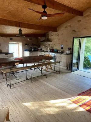 a large kitchen with wooden tables and a ceiling fan at Charming house in Tournissan