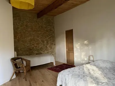 a bedroom with a bed and a stone wall at Charming house in Tournissan