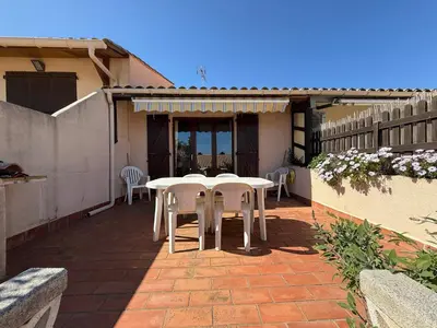 a patio with white tables and chairs on a house at AIG 160 – Villa T2 mezzanine – Résidence Les Villas du Port – Gruissan – 4/6 personnes in Gruissan