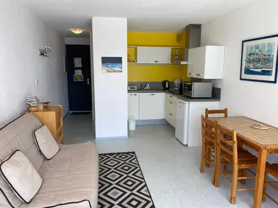 a living room and kitchen with a couch and a table at Studio 2 couchages – Entre port et plage – Résidence Presqu’île 2 à Gruissan in Gruissan