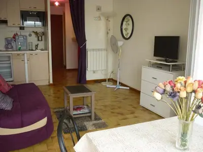 a living room with a couch and a table at Studio cabine – 2 couchages – Vue port – Résidence Le Chébeck – Gruissan in Gruissan
