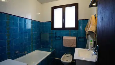 a blue tiled bathroom with a tub and a sink at AIG 55 – Chalet individuel – Avenue de la Jetée – Gruissan – 6/7 personnes in Gruissan