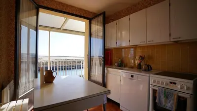a kitchen with white cabinets and a view of the ocean at AIG 55 – Chalet individuel – Avenue de la Jetée – Gruissan – 6/7 personnes in Gruissan