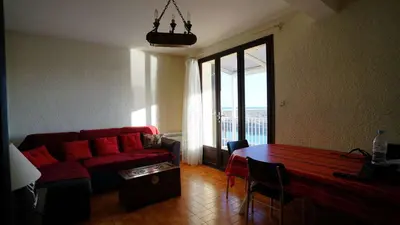 a living room with a red couch and a table at AIG 55 – Chalet individuel – Avenue de la Jetée – Gruissan – 6/7 personnes in Gruissan