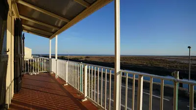 a balcony of a building with a view of the ocean at AIG 55 – Chalet individuel – Avenue de la Jetée – Gruissan – 6/7 personnes in Gruissan