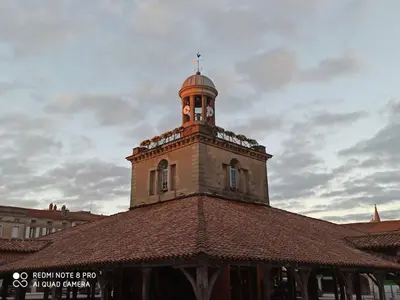 a building with a clock tower on top of it at Gîte Un Air d'Autan, labelissé 3 étoiles in Saint-Félix-Lauragais