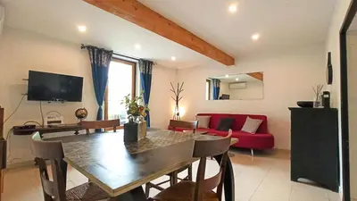 a living room with a table and a red couch at Gîte Un Air d'Autan, labelissé 3 étoiles in Saint-Félix-Lauragais