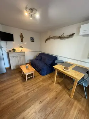 a living room with a blue couch and a table at Rez de jardin accès direct plage in Gruissan