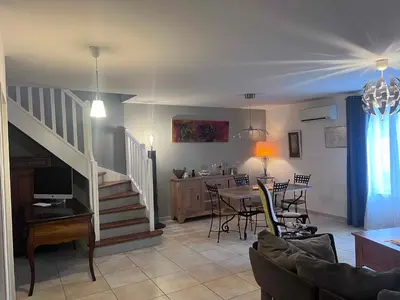 a living room with a staircase and a table and chairs at Bel appartement, Deux chambres, Deux salles de bain in Vinassan