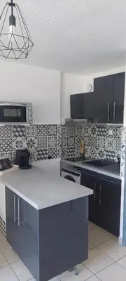 a kitchen with a white counter top and black cabinets at Studio à proximité des plages in Gruissan