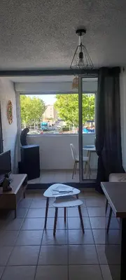 a living room with a table and a window at Studio à proximité des plages in Gruissan