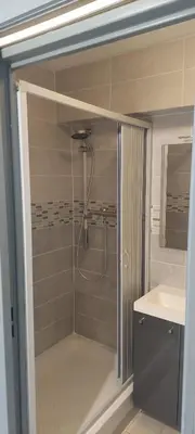 a bathroom with a shower with a sink and a mirror at Studio à proximité des plages in Gruissan