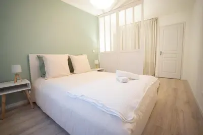 a white bed in a room with a window at Centre de Carcassonne 2min gare in Carcassonne