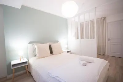 a white bedroom with a white bed and two lamps at Centre de Carcassonne 2min gare in Carcassonne