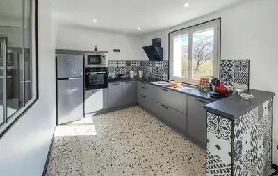 a large kitchen with white cabinets and a window at Maison calme avec vue sur les collines environnantes in Berlou
