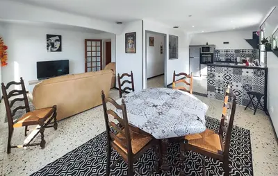 a living room with a table and a kitchen at Maison calme avec vue sur les collines environnantes in Berlou