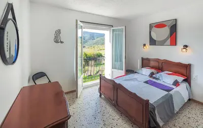 a bedroom with a bed and a large window at Maison calme avec vue sur les collines environnantes in Berlou