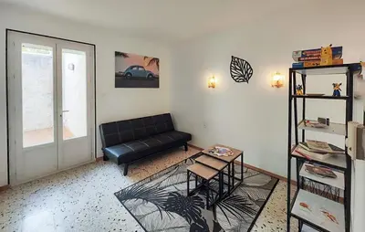 a living room with a black couch and a window at Maison calme avec vue sur les collines environnantes in Berlou