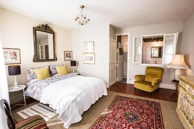 a bedroom with a bed and a chair and a mirror at Maison 1888 Carcassonne - Roof Terrace & Cité Views in Carcassonne