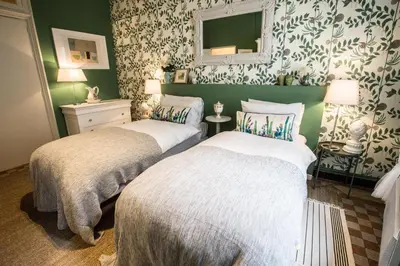 two beds in a room with green and white wallpaper at Maison 1888 Carcassonne - Roof Terrace & Cité Views in Carcassonne