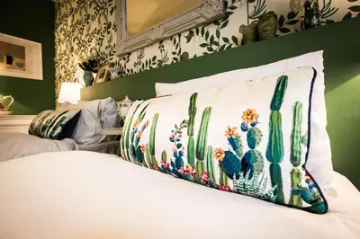 a bedroom with a bed with a cactus pillow at Maison 1888 Carcassonne - Roof Terrace & Cité Views in Carcassonne